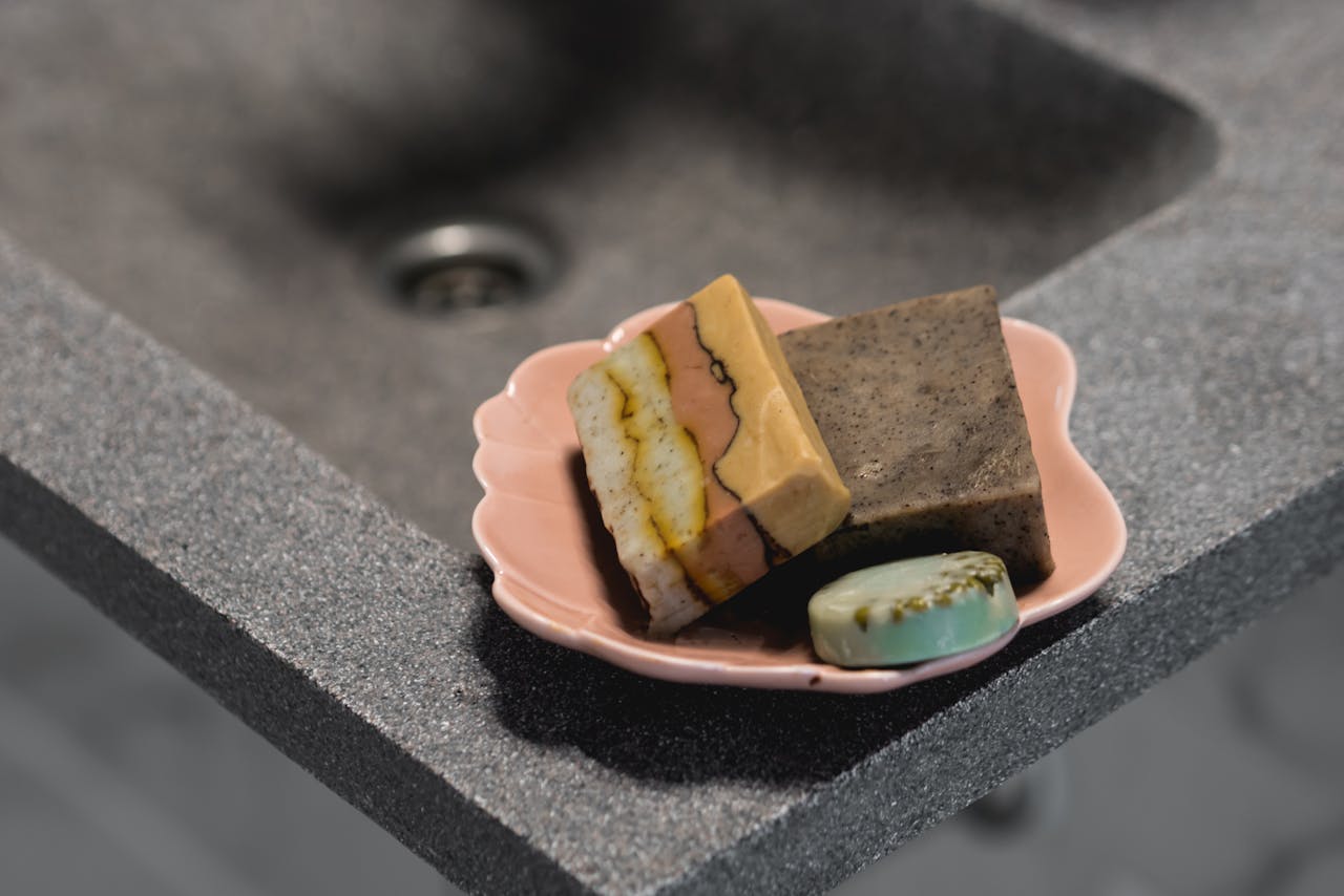 Close-up still life of handcrafted soaps on a pink tray, highlighting self-care and skincare essentials.