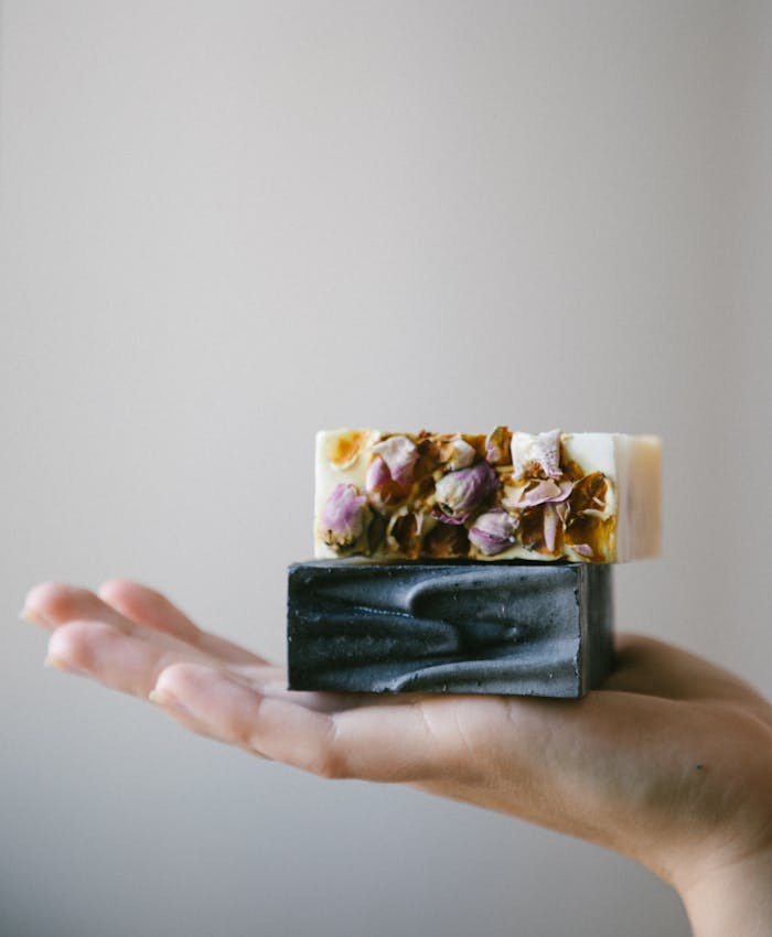 client-satisfaction-img Hand holding handcrafted floral and charcoal soaps, embodying natural skincare and sustainable beauty.